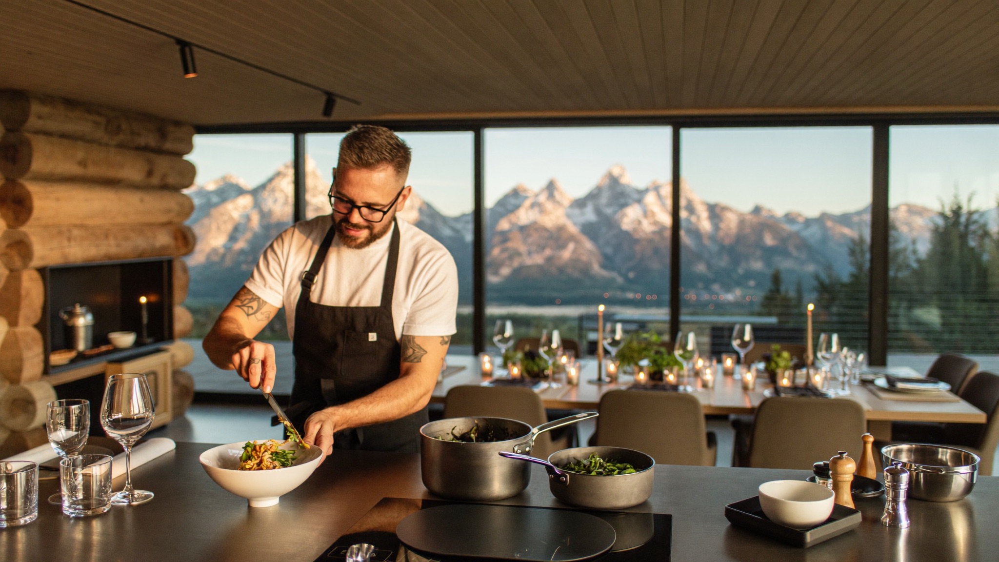 A private chef plating dinner in a Jackson Hole home with the Teton range through the windows